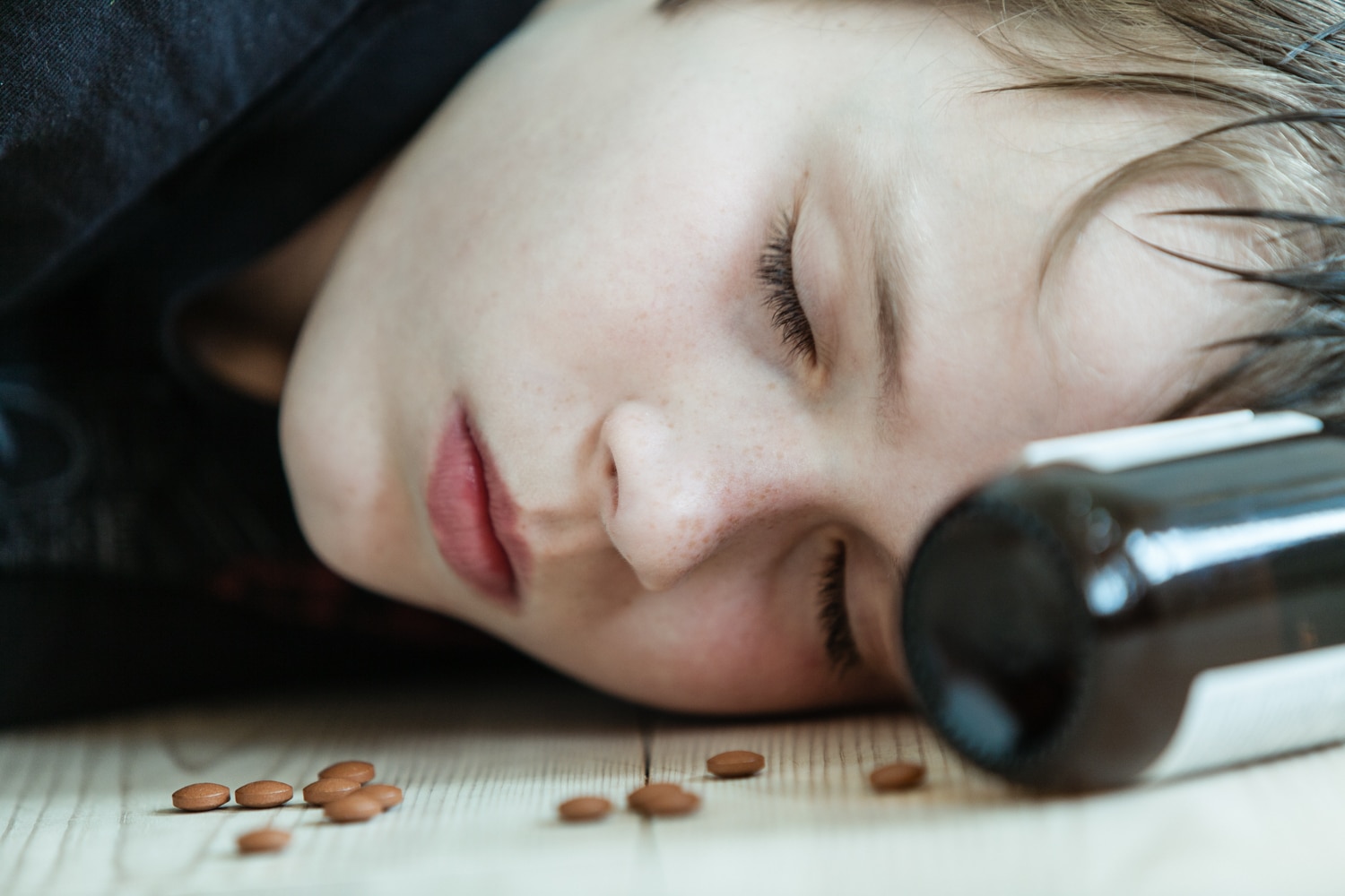 child with pills next to their face