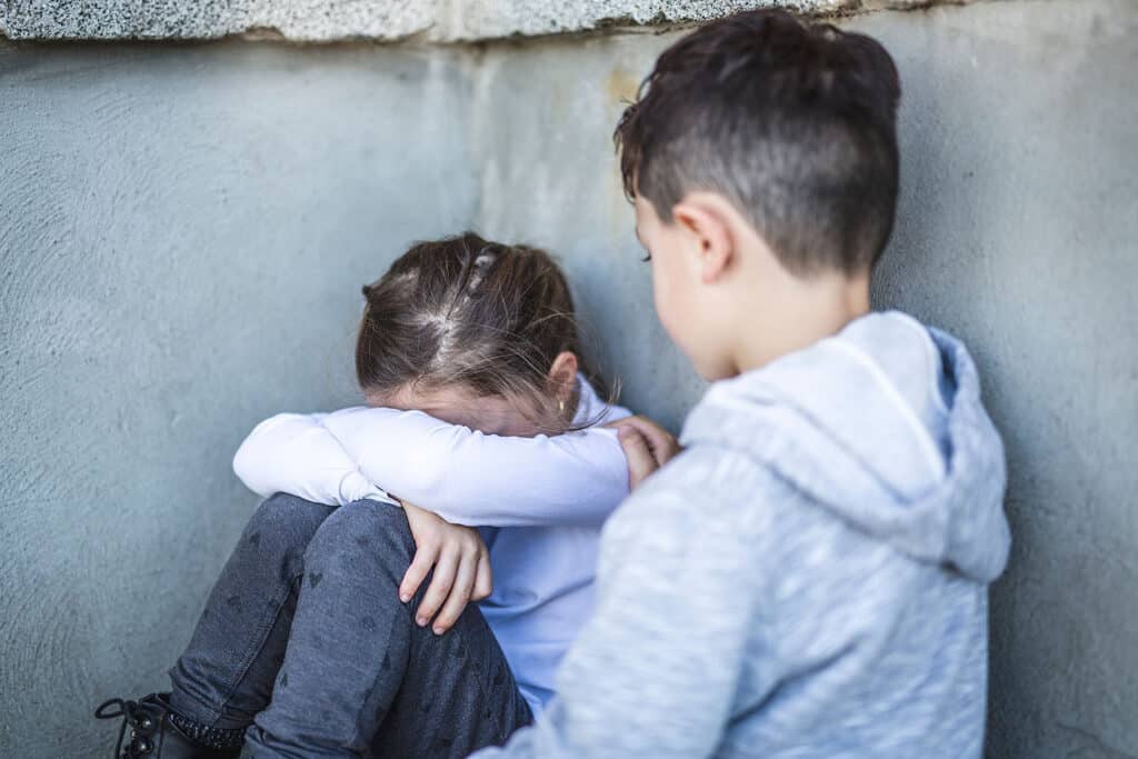 boy checking on sad girl with head in her arms