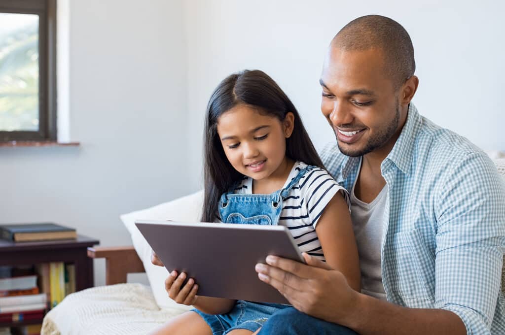 father and daughter smiling at tablet