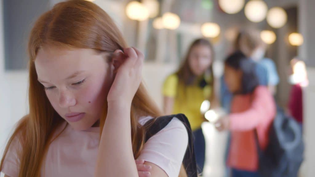 young girl being bullied by girls behind her