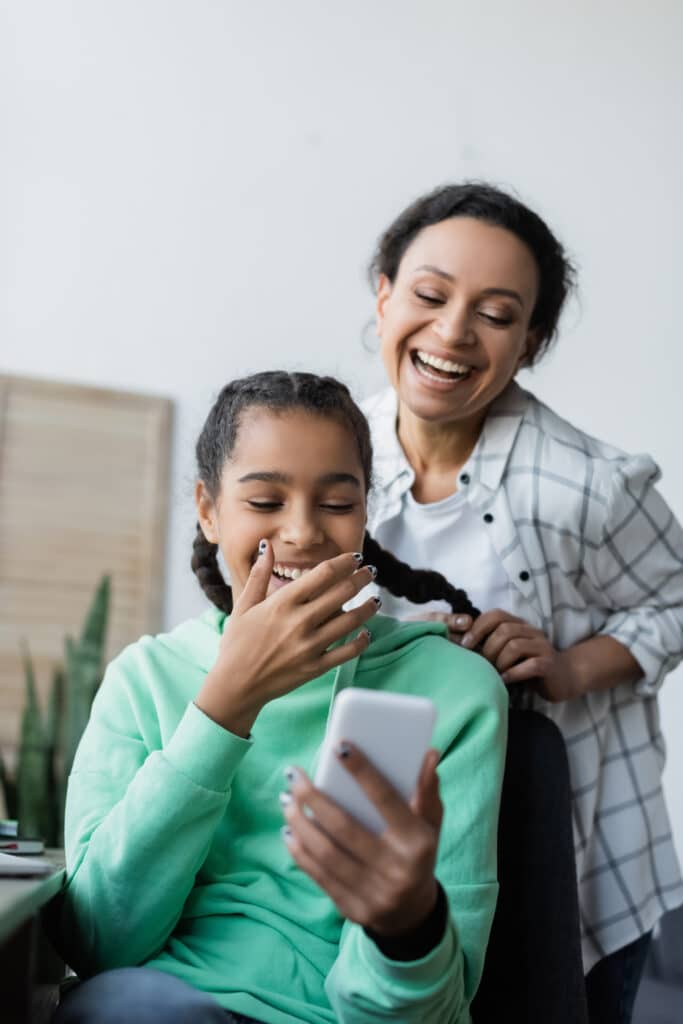 mother and daughter laughing at her cell phone