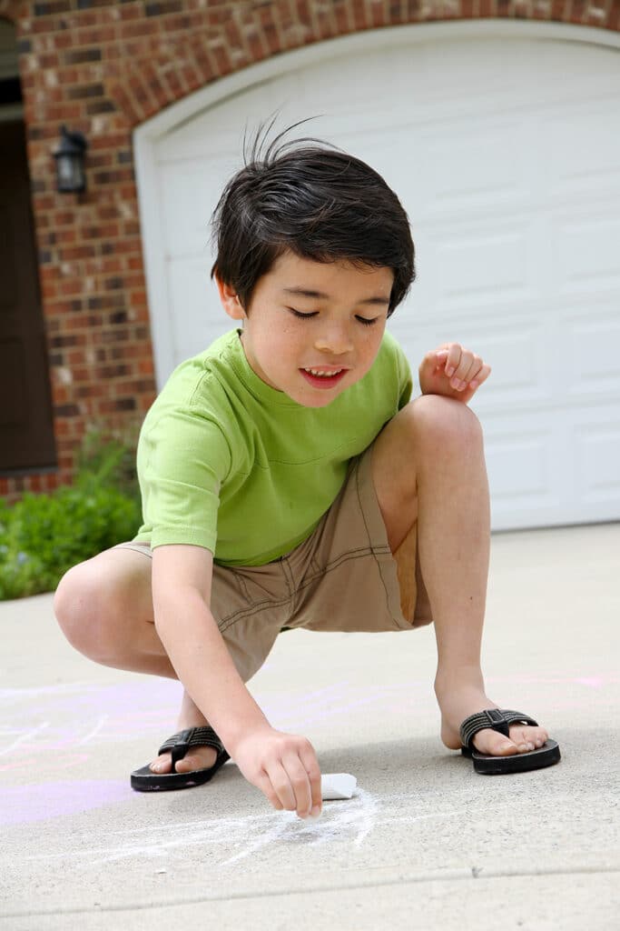 little boy playing with sidewalk chalk