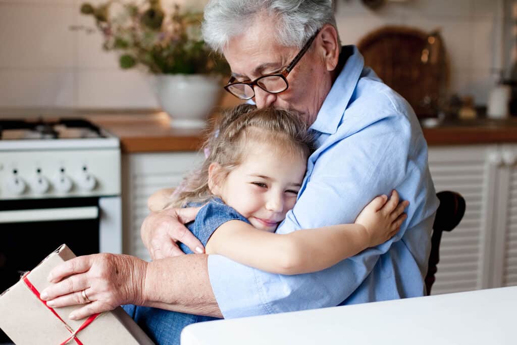 little girl hugs her grandpa who kisses her head