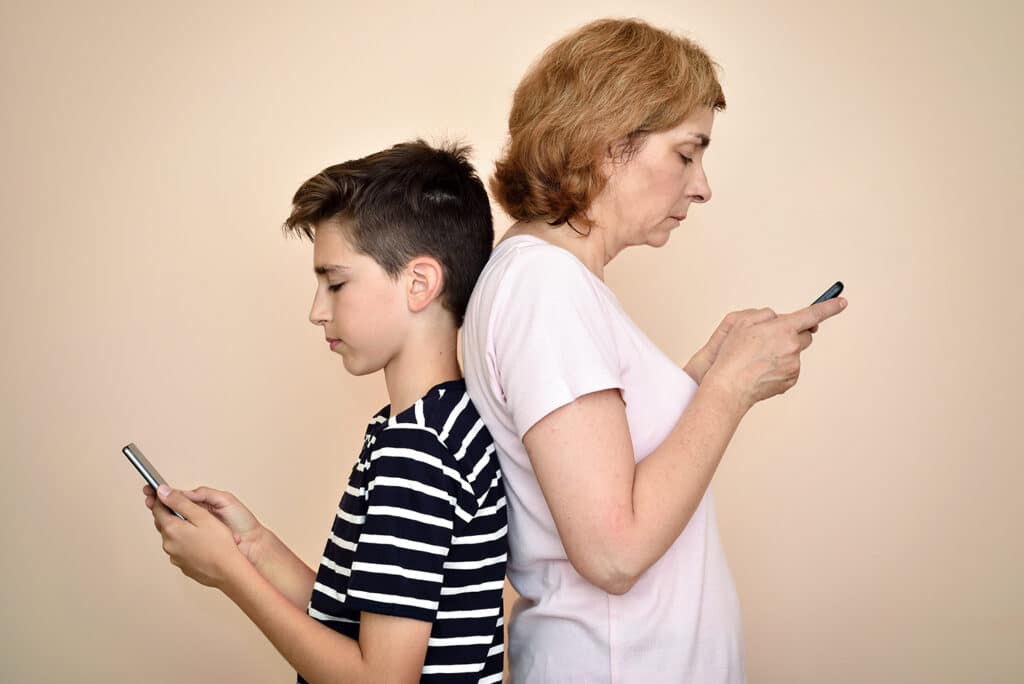 mother and son back to back on their phones