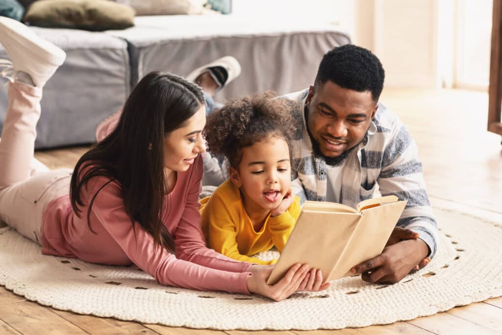 mother and father reading to daughter on the floor