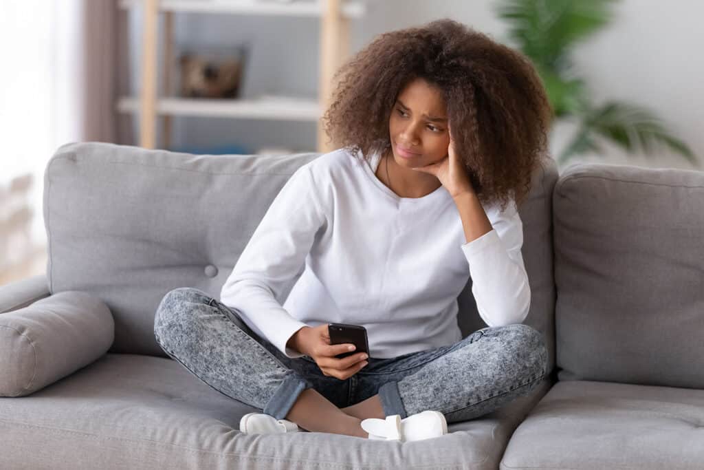 teen girl holding cellphone looking concerned