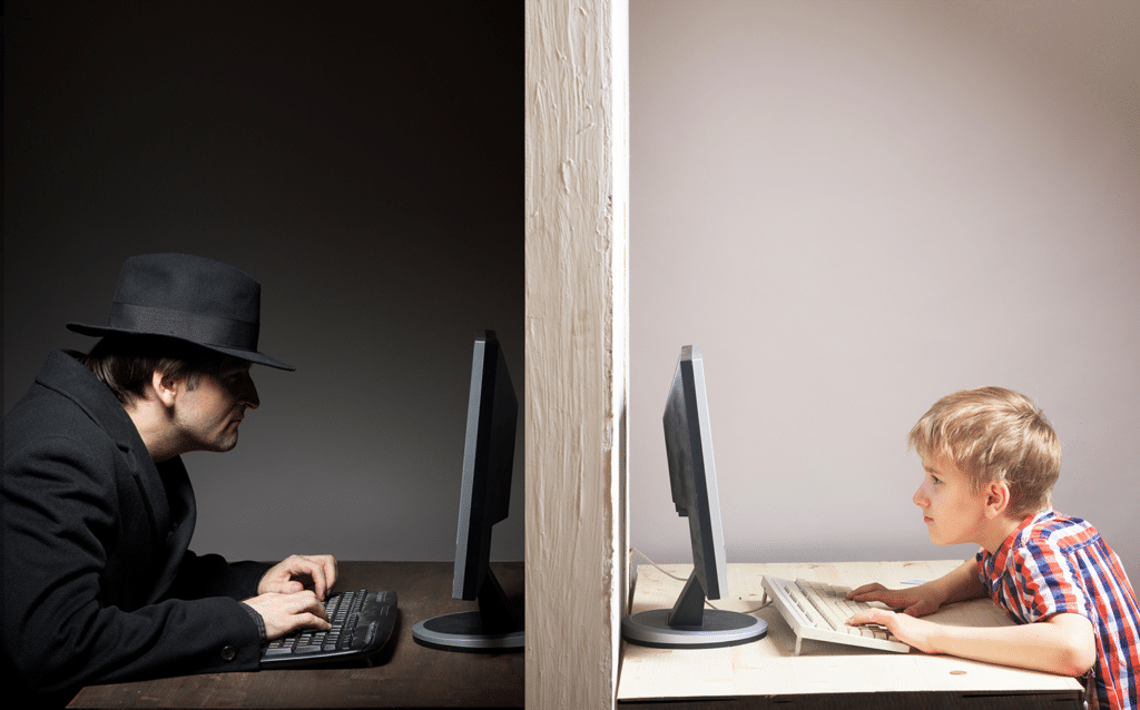 boy and sketchy man typing on computers with a wall separating them